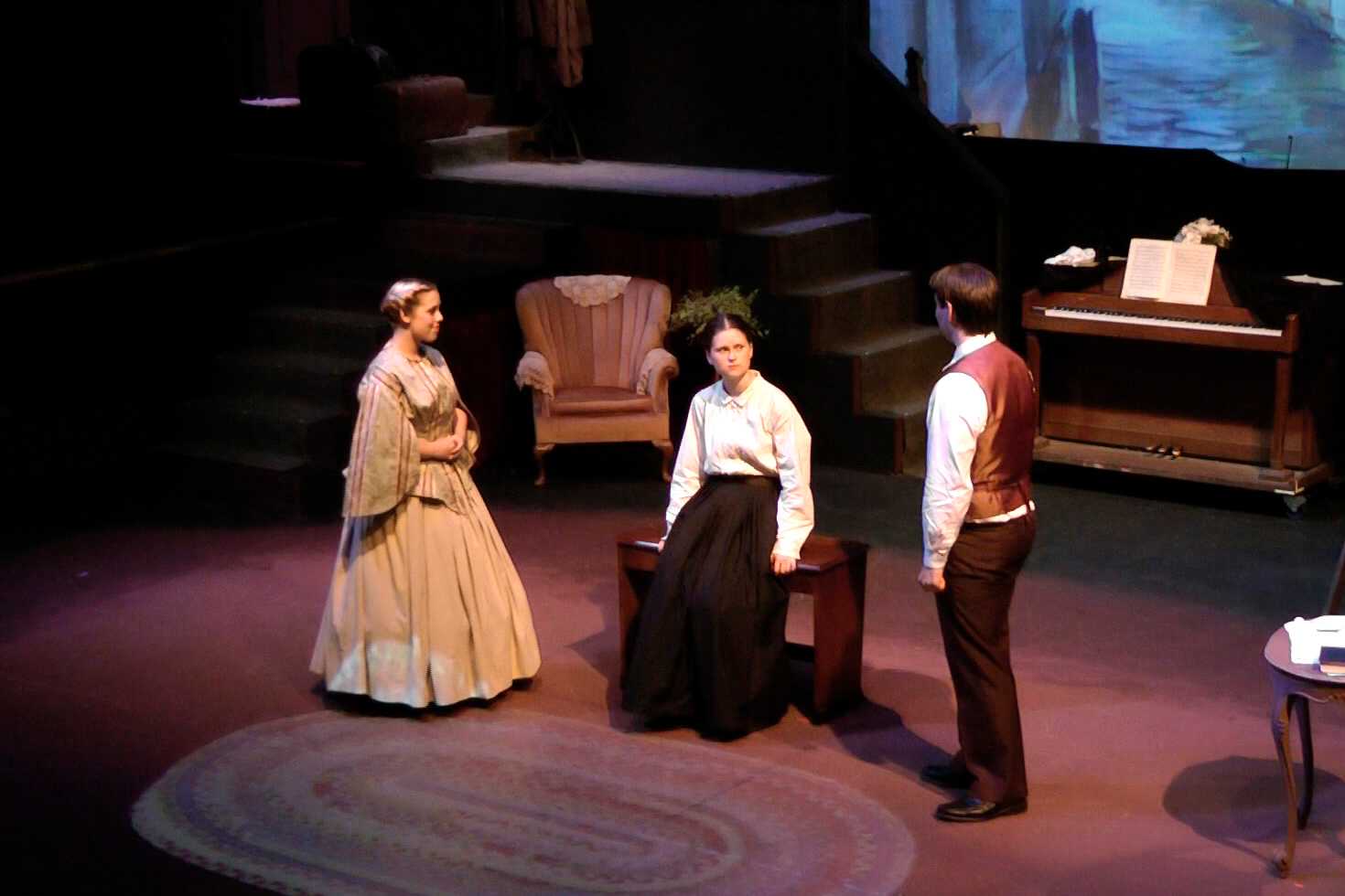 Three people in nineteenth century costume stand in a line.